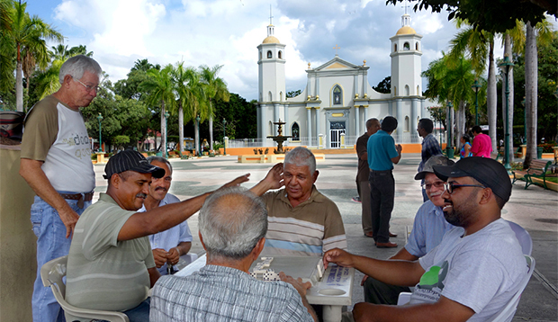 men playing dominos in the plaza in front of the GUayama church